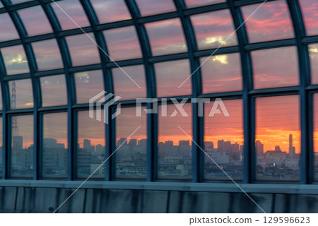 Osaka city skyline reflected in a glass structure during sunset, showing vibrant colors in the sky above Osaka, Japan 129596623