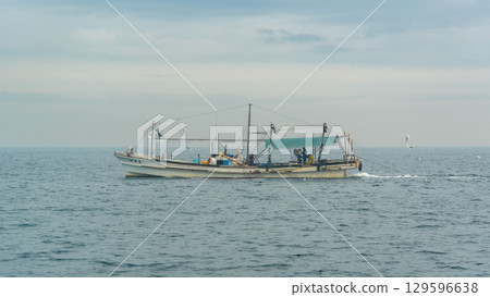 A lone fishing boat on a calm sea under a cloudy sky in Osaka bay in Japan 129596638