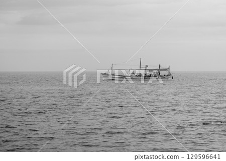 A lone fishing boat on a calm sea under a cloudy sky in Osaka bay in Japan A lone fishing boat on a calm sea under a cloudy sky in Osaka bay in Japan 129596641