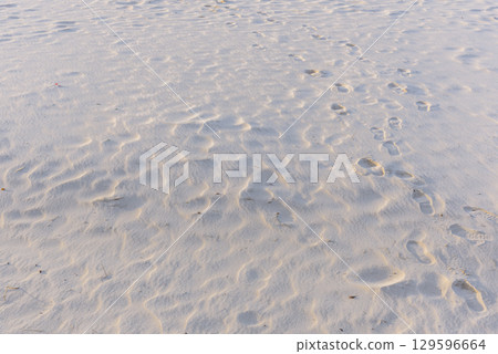 Footprints on a sandy beach with ripples from wind in the sand 129596664