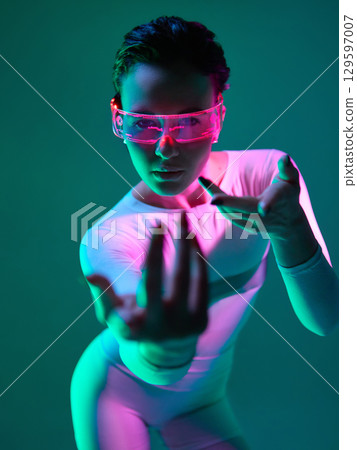 Woman in neon visor reaching forward with intense gaze Woman in neon visor reaching forward with intense gaze 129597007
