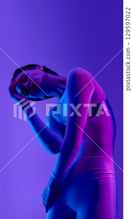 Artistic neon-lit woman fashion posing with futuristic elegance 129597022