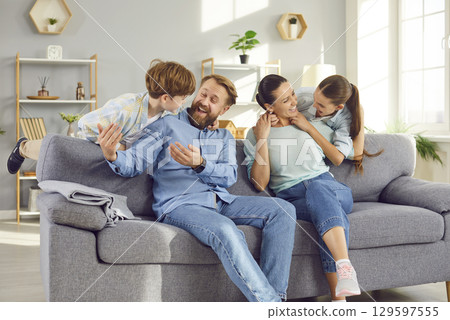 Young happy family sitting on sofa in the living room at home with kids having fun and smiling Young happy family sitting on sofa in the living room at home with kids having fun and smiling 129597555