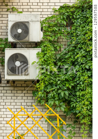 Air conditioners are installed on facade of building. device for comfortable living in hot weather. 129597588