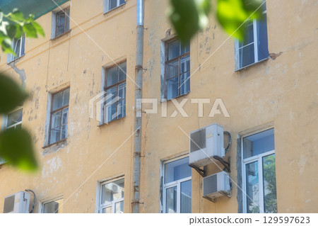 Air conditioners are installed on facade of building. device for comfortable living in hot weather. 129597623