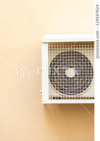 air conditioner in an anti-vandal grid is installed on wall of house.  129597624