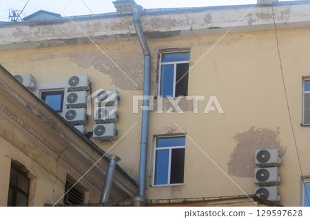 Air conditioners are installed on facade of building. device for comfortable living in hot weather. 129597628
