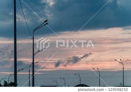 Silhouetted Streetlights Against a Dramatic Sky 129598232