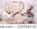 Couple enjoys cozy Christmas moments together with their dog on the couch. Concept of love, family, pets and holiday. 129598516