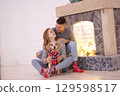 Couple enjoys cozy moments with their dog by the fireplace. Concept of love, family and dogs. 129598517