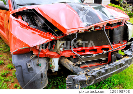 Damaged red pickup truck with severe front end collision in rural setting during daytime 129598708