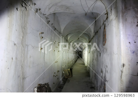 A long, narrow hallway with a white wall 129598963