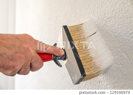 House painter worker painting a wall white. Building. 129598979