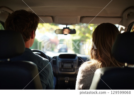 Couple driving together, view from backseat, enjoying sunny road trip with carefree happiness and open road ahead 129599068