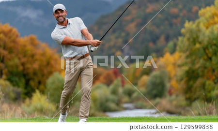 Happy golfer in beige pants makes a powerful golf swing on a picturesque autumn course 129599838