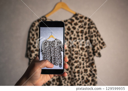 Close up of hands holding smartphone camera capturing old clothes items for online resale resources. Image for second hand concept. Close up of hands holding smartphone camera capturing old clothes items for online resale resources. Image for second hand concept. 129599935
