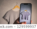 Woman taking photo of her old clothes for resale. Second hand concept. Closet organization. 129599937