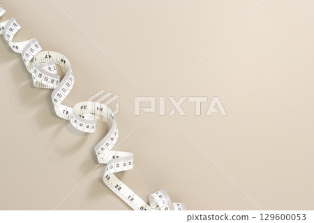 White measuring tape creating a border on a beige background, ideal for weight loss, diet or tailoring. Copy space White measuring tape creating a border on a beige background, ideal for weight loss, diet or tailoring. Copy space 129600053