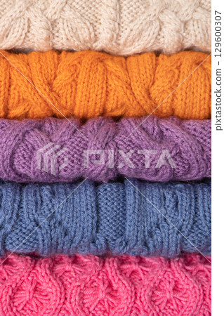 Abstract knitted background from set of multicolored knitted clothes stacked. Space for text. Knitting warm clothes, blankets and blankets. Concept of home needlework 129600307