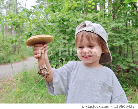 Children walking in the forest and gather mushrooms. happy child is picking mushrooms in the forest. Cute emotional boy in the forest. Children walking in the forest and gather mushrooms. happy child is picking mushrooms in the forest. Cute emotional boy in the forest. 129600422