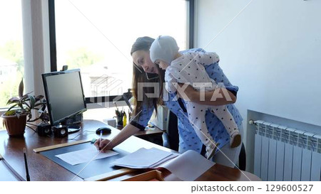 Multitasking businesswoman juggles work and family life while caring for her baby in her home office 129600527