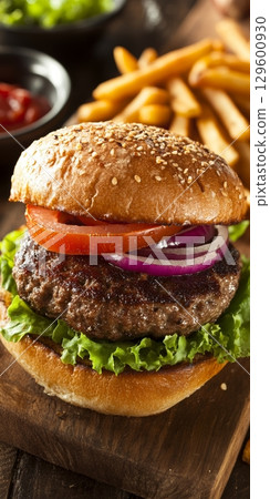 Delicious Classic American Hamburger with Fresh Lettuce, Tomato, and Crispy French Fries on Plate 129600930