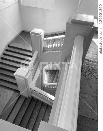 Light pours through the windows, highlighting a stunning stairwell with curved railings and stone steps, enhancing the interiors beauty. 129601860