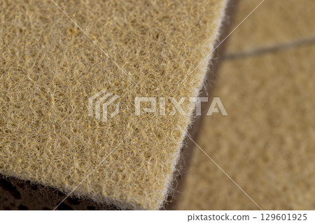 glued and tightly intertwined synthetic sand-colored threads on a sponge that is used for cleaning and washing, closeup 129601925
