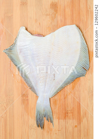 Thawed headless flounder on a wooden cutting board. Thawed headless flounder on a wooden cutting board. 129602242