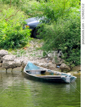 Relaxing Moment by the Riverbank With a Boat and Car Nestled in the Lush Landscape of Montenegro Relaxing Moment by the Riverbank With a Boat and Car Nestled in the Lush Landscape of Montenegro 129602312