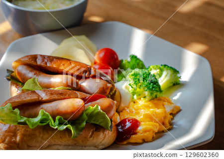 A Western-style breakfast plate with hot dogs, scrambled eggs, and vegetables 129602360