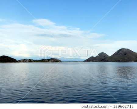 Discover Skadar Lakes Tranquil Beauty: Serene Waters and Majestic Mountains Await! 129602715