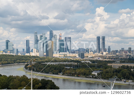 Luzhniki Park offers a stunning view of the Moscow City skyline, framed by lush greenery and dynamic clouds above. 129602736