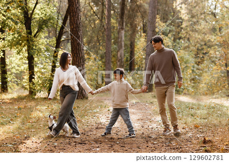 Family with child and dog walking in autumn forest 129602781