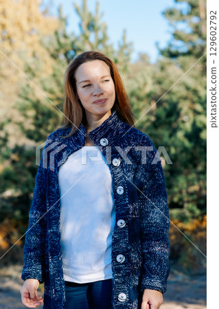 Female portrait. Beautiful young girl with long dark hair on a sunny autumn day outdoors. Vertical photo. High quality photo 129602792