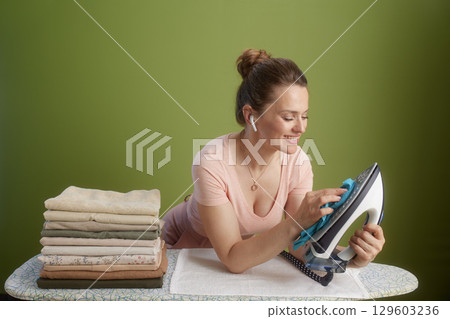 Woman cleaning iron on board, light pink top & blush skirt Woman cleaning iron on board, light pink top & blush skirt 129603236