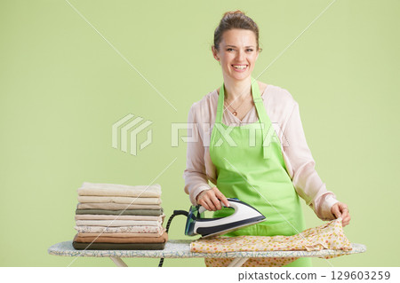 Happy woman ironing clothes in cheerful home scene Happy woman ironing clothes in cheerful home scene 129603259