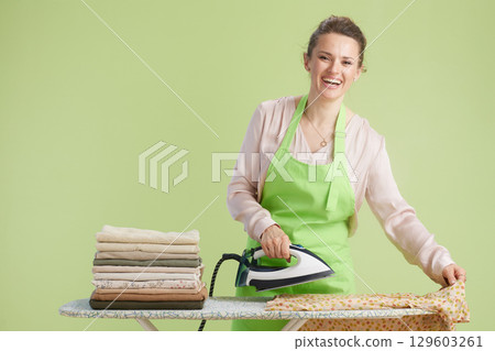 Smiling housewife ironing clothes with green backdrop Smiling housewife ironing clothes with green backdrop 129603261