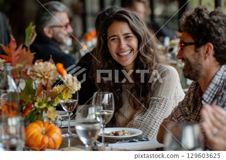 Smiling Woman Enjoying Autumn Feast Gathering with Friends at Festive Table Smiling Woman Enjoying Autumn Feast Gathering with Friends at Festive Table 129603625