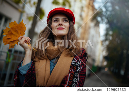 pensive young woman in red hat with autumn leafs and scarf 129603883