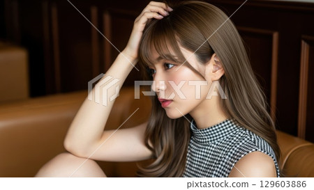 Profile of beautiful woman lost in thought on sofa in luxury lounge 129603886