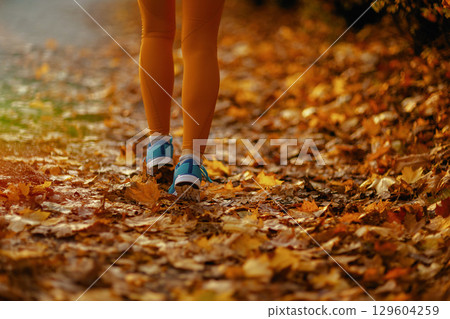 Closeup on female in fitness clothes in park walking 129604259