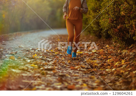 Stylish woman in fitness clothes in park running Stylish woman in fitness clothes in park running 129604261