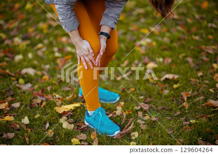 woman in fitness clothes in park having leg pain 129604264