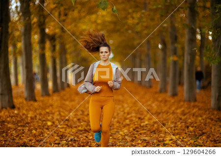 trendy female in fitness clothes in park running 129604266