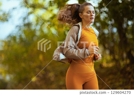 modern woman in fitness clothes in park jogging modern woman in fitness clothes in park jogging 129604270