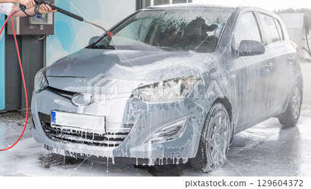 Man cleaning car. Spray hose foam soap. Car wash water shine exterior. Man cleaning car. Spray hose foam soap. Car wash water shine exterior. 129604372