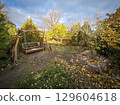 Old country cottage courtyard with a large bench, swing. Large bench swing in garden in autumn 129604618