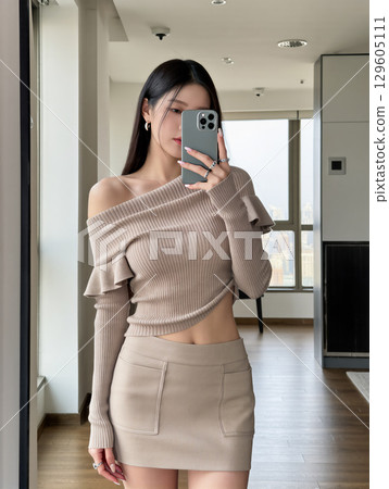 一位身穿米色服裝的女士對著鏡子自拍 一位身穿米色服裝的女士對著鏡子自拍 129605111