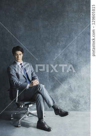 A businessman sitting in a chair A businessman sitting in a chair 129605815